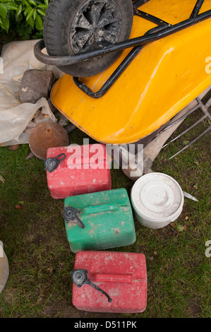 Close-up of building tools & garden landscaping equipment at end of a working day (upturned wheelbarrow, pickaxe, fuel cans) - Yorkshire, England, UK. Stock Photo