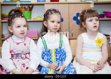 Cute boys and girls in Russian kindergarten sitting on the chairs in classroom. Russia Stock Photo