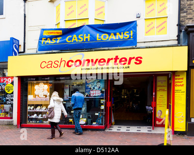 A couple looking in the window of a branch of Cash Converters offering to cash cheques and arrange cash advances and loans Stock Photo