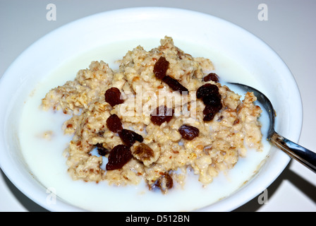 Bowl cooked whole grain oatmeal cereal skim milk Sultana raisins cholesterol lowering breakfast low sodium Stock Photo