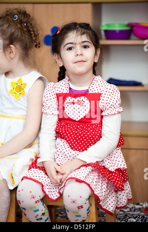 Cute boys and girls in Russian kindergarten sitting on the chairs in classroom. Russia Stock Photo