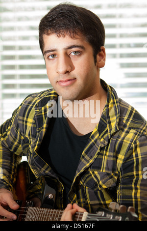 Close up on an attractive youth playing guitar Stock Photo