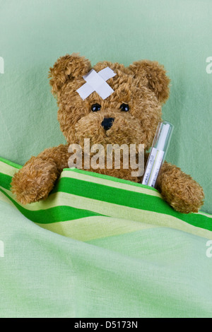 bear in bed with thermometer and plaster Stock Photo