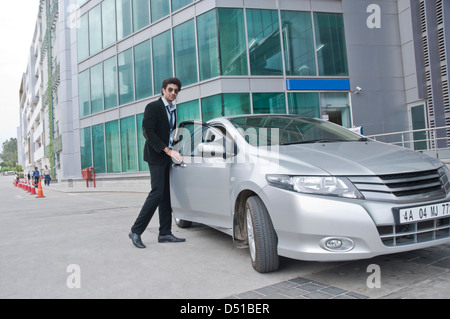 Businessman getting into a car in front of an office building Stock Photo
