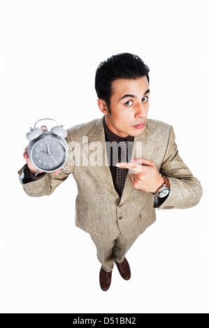 Angry businessman pointing towards an alarm clock Stock Photo