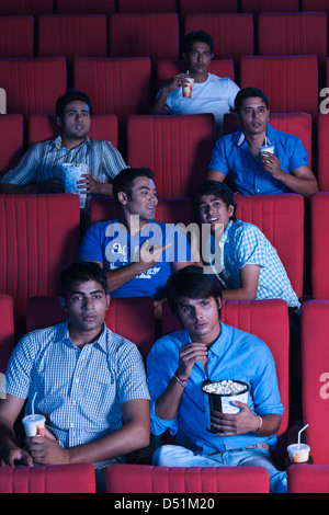 Youngsters enjoying movie with popcorns in a cinema hall