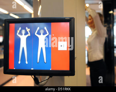 A woman stands inside a body scanner at the airport in Hamburg, Germany, 27 September 2010. Two of such devices are on a two-year trial run, their use is optional. Photo: Marcus Brandt Stock Photo