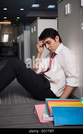 Businessman leaning against a cabinet in the corridor Stock Photo