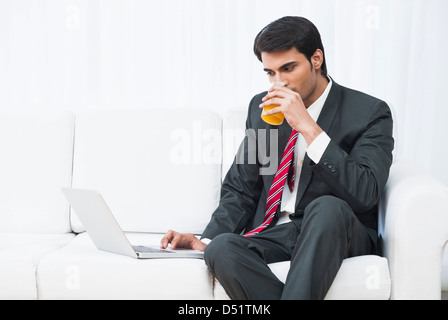 Businessman using a laptop and drinking juice Stock Photo