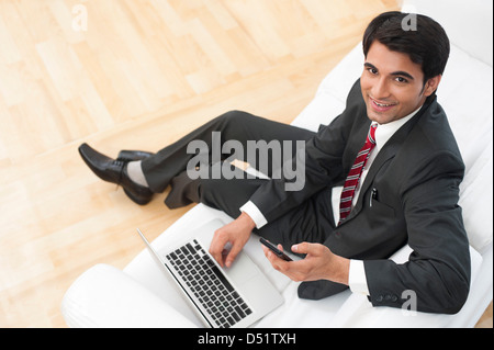 Businessman using a mobile phone while working on a laptop Stock Photo