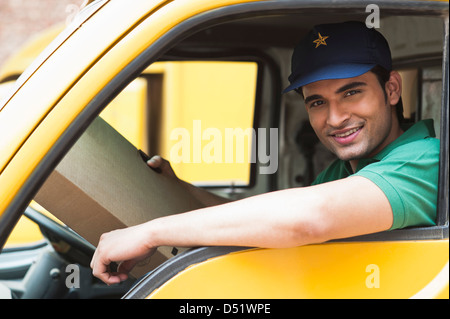 Delivery man sitting in his van and smiling Stock Photo
