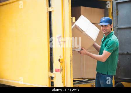 Delivery man unloading cardboard boxes from a van Stock Photo