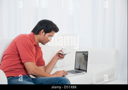 Man using a laptop and having coffee Stock Photo
