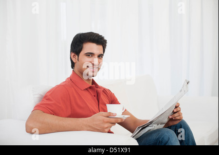 Happy man reading a newspaper while having coffee Stock Photo