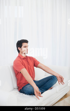 Man practicing yoga on a couch Stock Photo