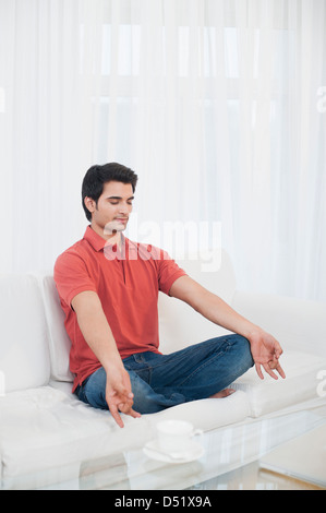 Man practicing yoga on a couch Stock Photo