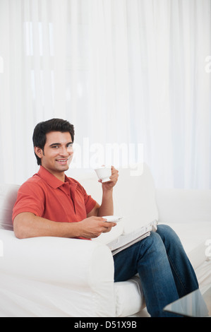 Man sitting on a couch and drinking coffee Stock Photo