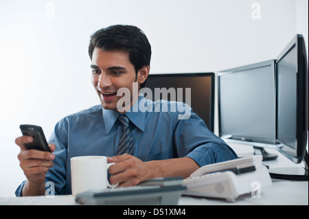 Businessman using a mobile phone while drinking coffee Stock Photo