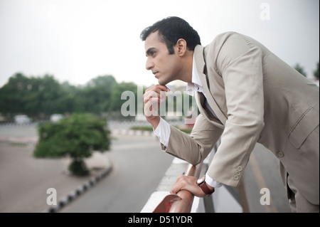 Businessman leaning against flyover railing and looking thoughtful Stock Photo