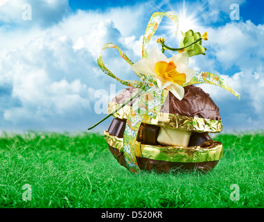 Chocolate Easter Egg and praline with Bow on green grass and blue sky Stock Photo