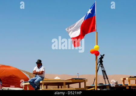 A family member of the trapped miners waits next to the Chilean flag on the premises of the San Jose copper mine in Copiapo, Chile, pictured on 8 October 2010. The countdown to rescue the 33 trapped Chilean miners is running. The first miners are expected to be salvaged this upcoming Tuesday to see the day of light for the first time in two months. The trapped miners are to be lift Stock Photo