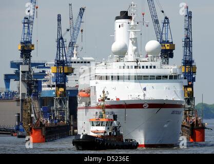 (FILE) - A picture dated 02 June 2010 shows the damaged ship 'Germany' that is pulled to dock 10 of the shipyard 'Blohm + Voss' by towboats at the harbour in Hamburg, Germany. Gisa and Hedda Deilmann, daugters of the company founder Peter Deilmann, have pulled out of the management of the company. They wish to work as ambassadors of the 'Germany' in the future. Photo: Maurizio Gamb Stock Photo