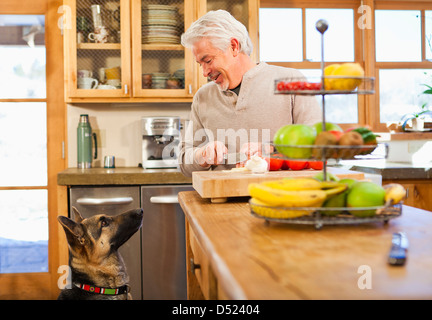 Hispanic man with begging dog in kitchen Stock Photo