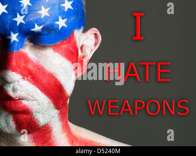 Man with his face painted with the flag of USA and the text 'I hate weapons'. The man have his eyes closed. Stock Photo