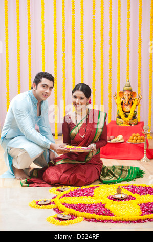 Maharashtrian couple making flower rangoli during ganesh chaturthi festival Stock Photo