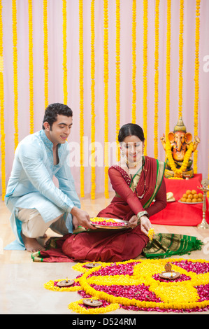 Maharashtrian couple making flower rangoli during ganesh chaturthi festival Stock Photo