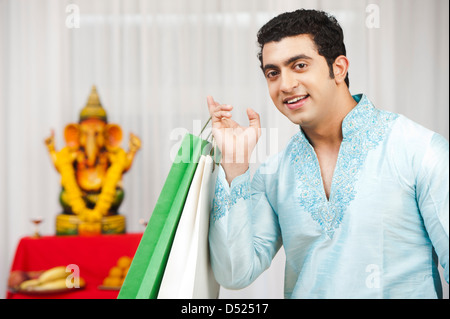 Maharashtrian man holding shopping bags and smiling during ganesh chaturthi festival Stock Photo