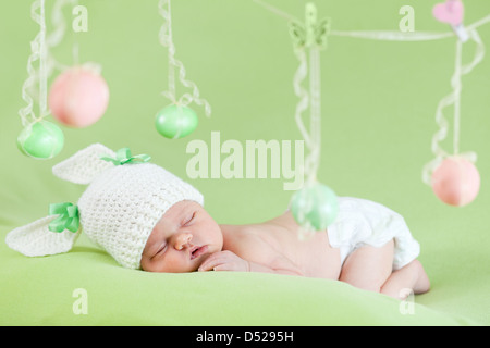adorable baby dressed in Easter bunny cap with eggs Stock Photo