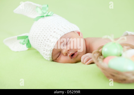 adorable baby dressed in Easter bunny cap with eggs Stock Photo