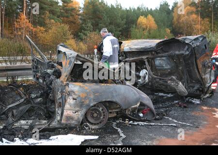 A policemen takes pictures of burnt-out vehicles after a severe car crash south of Berlin in Beelitz, Germany, 30 October 2010. Four people died in the accident that involved three cars and three trucks on Autobahn 9. Photo: NESTOR BACHMANN Stock Photo