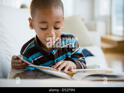 African American boy reading book on sofa Stock Photo