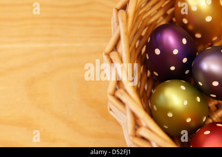 Closeup of five colored easter eggs in the basket on the wooden background Stock Photo