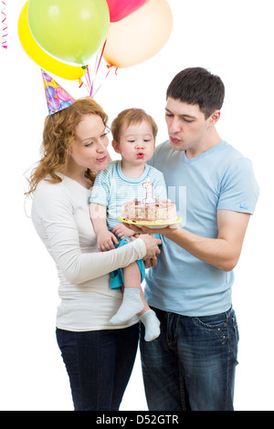 kid with parents celebrating birthday and blowing candles on cake Stock Photo