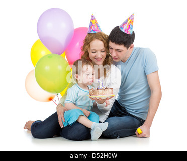 kid with parents celebrating birthday and blowing candles on cake Stock Photo