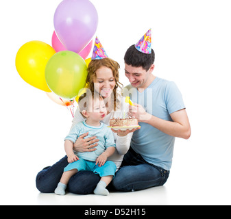 child boy with parents celebrating birthday and blowing candles on cake Stock Photo