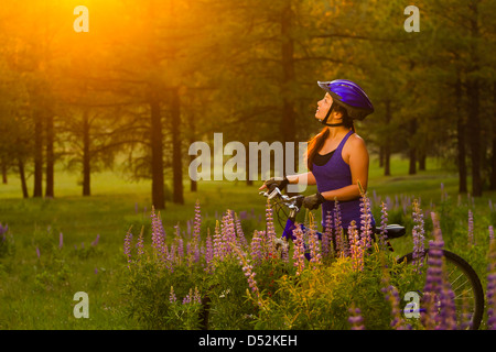 Chinese woman pushing mountain bike in meadow Stock Photo