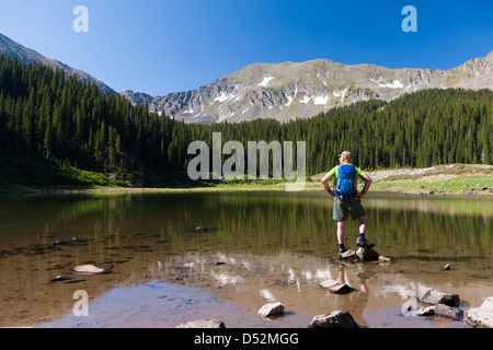 Caucasian hiker standing on rocks in lake Stock Photo