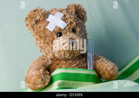 bear in bed with thermometer and plaster Stock Photo