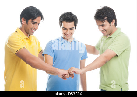 Three friends joining their hands and smiling Stock Photo