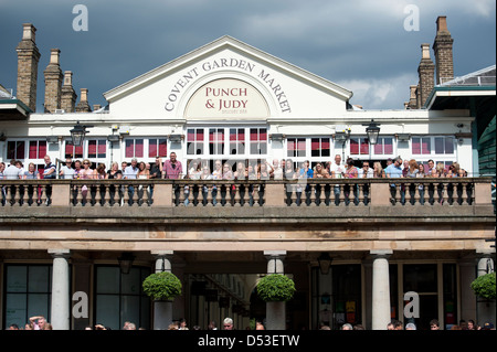 Crowds watching buskers at the Punch and Judy Pub, in front of St Pauls Church, Covent Garden Plaza, London Stock Photo