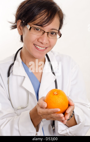 Attractive filipino asian nurse doctor holding orange Stock Photo