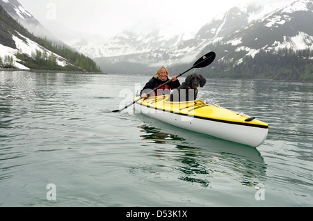 Woman sea kayaking with dog in Glacier Bay National Park, Alaska. Stock Photo