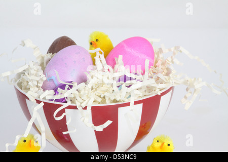 Colored eggs in a bowl filled with paper straw, decorated for Easter. Stock Photo