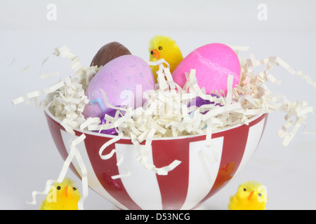 Colored eggs in a bowl filled with paper straw, decorated for Easter. Stock Photo