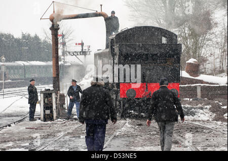Bridgnorth, Shropshire, UK. 23rd March 2013. The Severn Valley Railway 'Spring Steam Gala' weekend is affected by the Winter weather. In a snowstorm a steam engine is topped up with water from the vintage water bowser at Bridgnorth depot.  Credit:  John Bentley / Alamy Live News Stock Photo