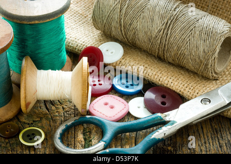 Spools of threads and buttons on old wooden table Stock Photo